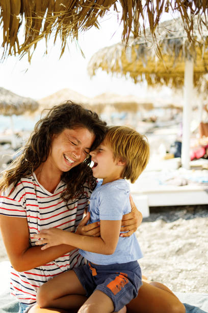 Cheerful single mother and son having fun on the beach. Cheerful mother and son having fun during summer day on the beach. family beach vacations travel stock pictures, royalty-free photos & images