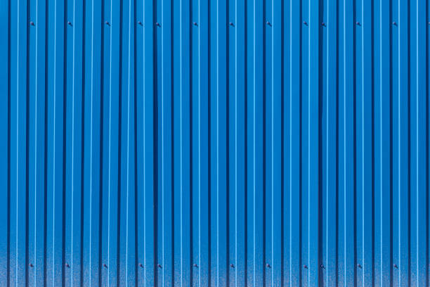 Fence made of blue profiled sheeting with mud splashes in the lower part Fence made of blue profiled sheeting with mud splashes in the lower part corrugated iron stock pictures, royalty-free photos & images