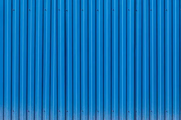 Photo of Fence made of blue profiled sheeting with mud splashes in the lower part