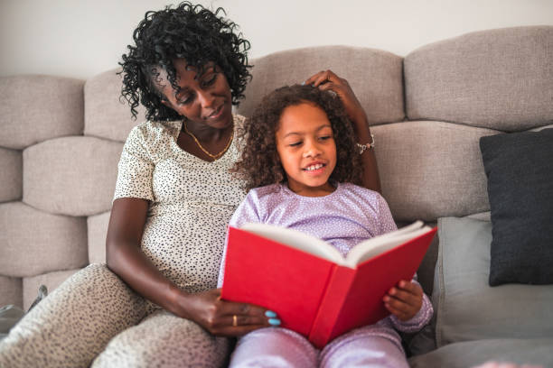 istock Multiracial Mother And Daughter Reading A Book In Bed 1403217564