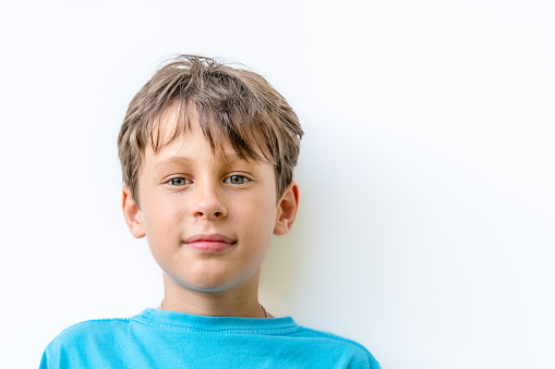 Portrait of a handsome white Eastern European 9 year old boy. The child looks directly into the camera with a barely perceptible smile. Copy space