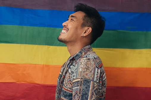 Happy man smiling and standing with pride flag. Gender Equality and LGBTQ concept.