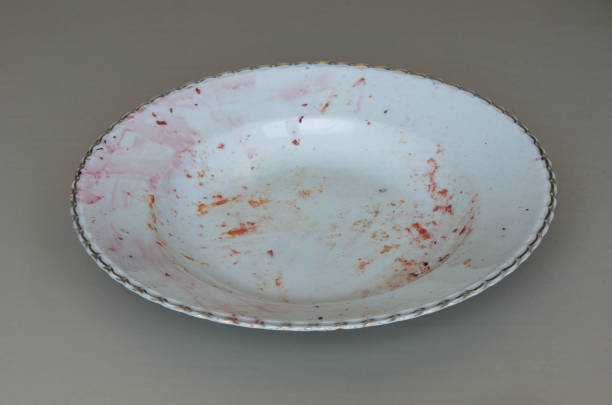 istock Empty dirty plate with gold rim on gray background 1403223034