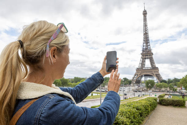 istock Young woman using mobile phone in Paris at the Eiffel Tower 1403224646