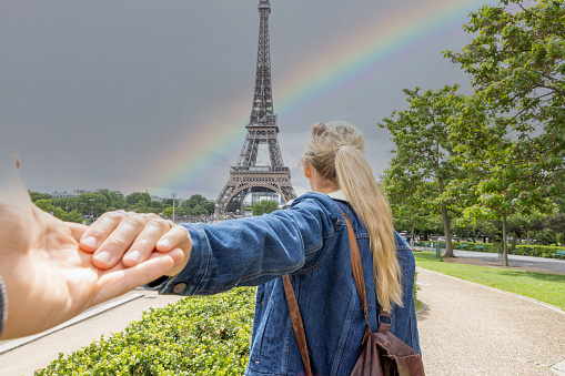 Man's personal perspective holding girlfriend's hand, she is leading him to the famous landmark. Couple travel in cities concept. Paris, France