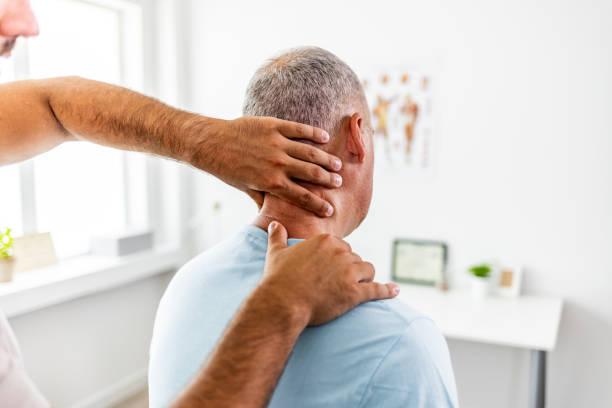 Neck pain medical exam Mature man shares symptoms with his doctor. chiropractor stock pictures, royalty-free photos & images