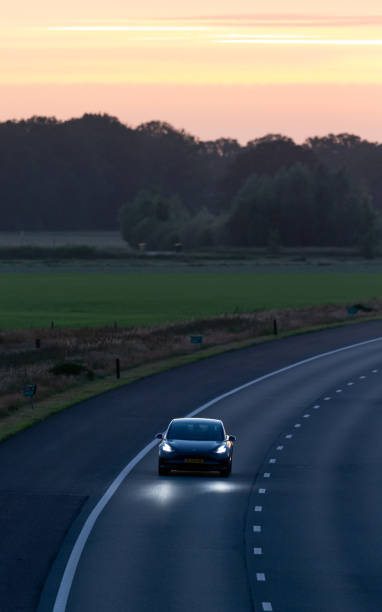 Dutch 2020 electric Tesla Model 3 approaching on the A35 at sunset stock photo