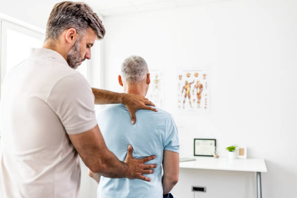 Mature man having chiropractic back adjustment. Confident successful mature doctor at hospital chiropractor photos stock pictures, royalty-free photos & images