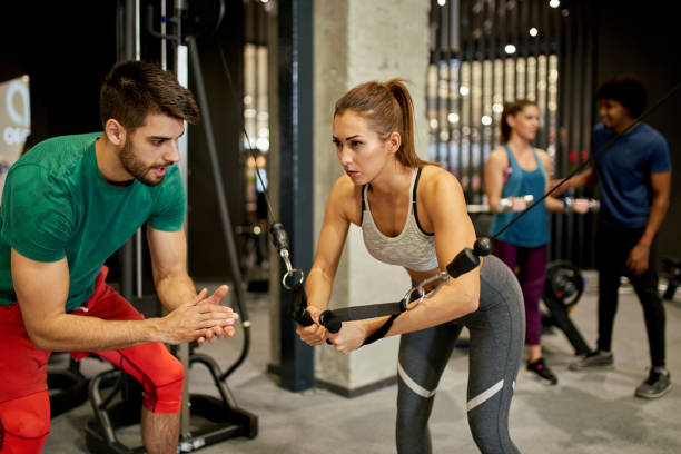 istock Woman working out on exercise machine with instructor at gym 1403229214