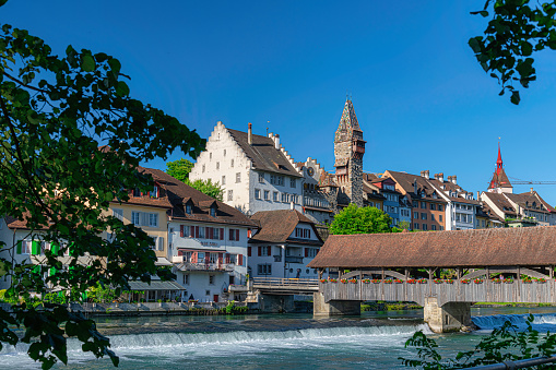 The medieval wooden bridge over Reuss river in Bremgarten is very known and was build 1281. Rebuild 1953. In background the house of administration of abbey Muri-Amthof with the prominent tower.