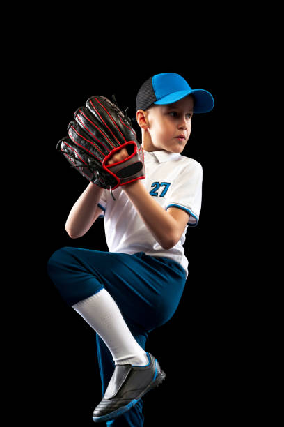 istock Dynamic portrait of little baseball player, pitcher in blue-white uniform training isolated on black studio background. Concept of sport, achievements, studying, competition 1403231065