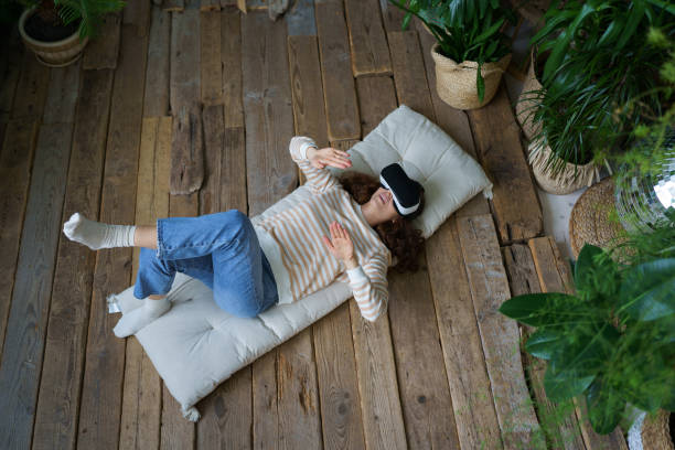 istock Impressed young woman getting VR experience using virtual reality headset glasses at home 1403237384