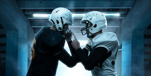 Rivals. Close-up two men, american football players in sport uniform and helmets standing opposite each other before start of match. Sport, game, competition.