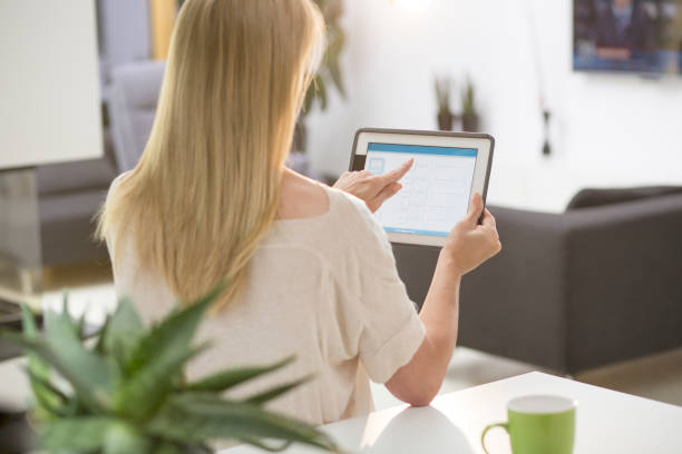istock Woman using smart home automation in living room with digital tablet 1403237500