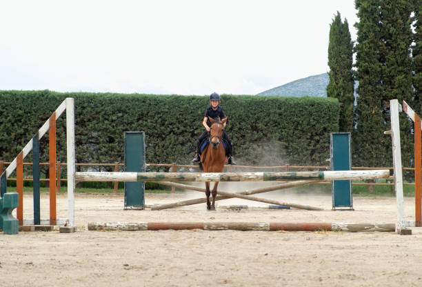 istock Kid on horse jumping over barrier. 1403238062