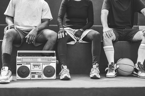 Group of young african people listening music outdoor after basketball match - Focus on boombox stereo - Black and white editing