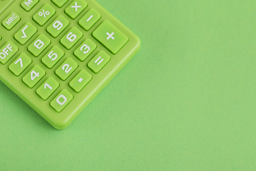 Green calculator on Green background. Copy space. Environmental, Social, Corporate Governance.