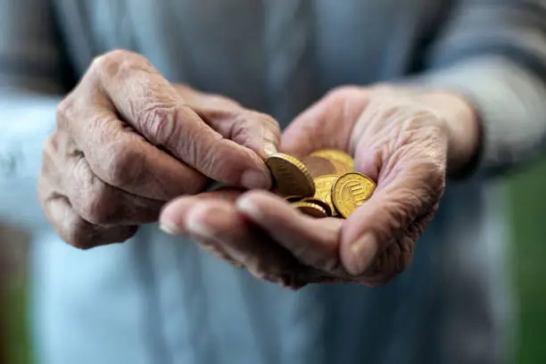 close-up of an older womans hand holding coins and counting
