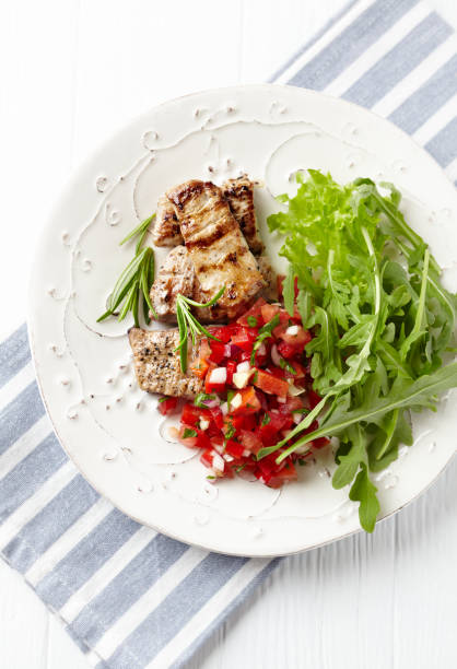 istock Grilled Pork Tenderloin with Tomato Salsa and Arugula. Bright background. Top view. Copy space. 1403243144