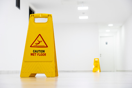 Yellow Caution slippery wet floor sign on the wet ground