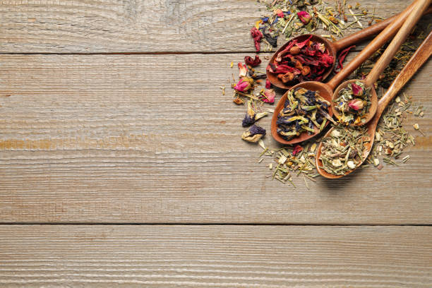 istock Spoons with different teas on wooden table, flat lay. Space for text 1403245346