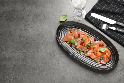 Delicious salmon carpaccio served on grey table, flat lay. Space for text