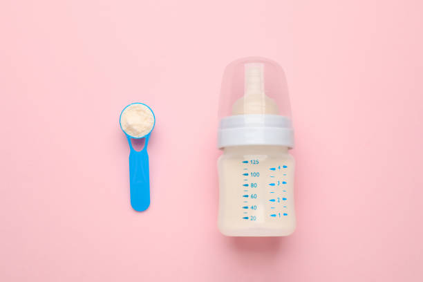 istock Feeding bottle with infant formula and powder on pink background, flat lay 1403247276