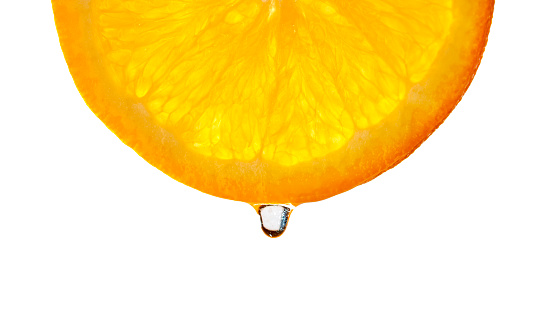 Close-up of orange fruit slice with water drop against white background.