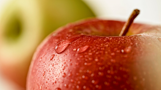 Close-up of apple with water drops against white background.