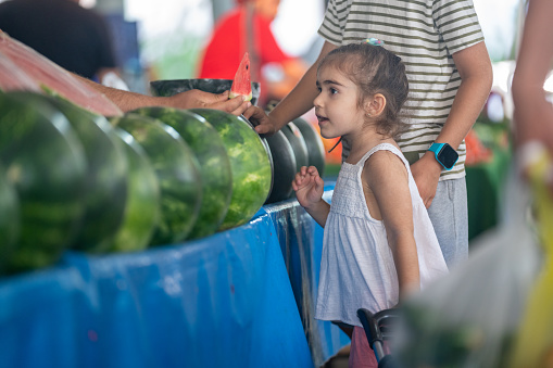 Photo of 4 years old sister and 9 years old brother shopping in farmer's market. Shot under daylight with a full frame mirrorless camera.