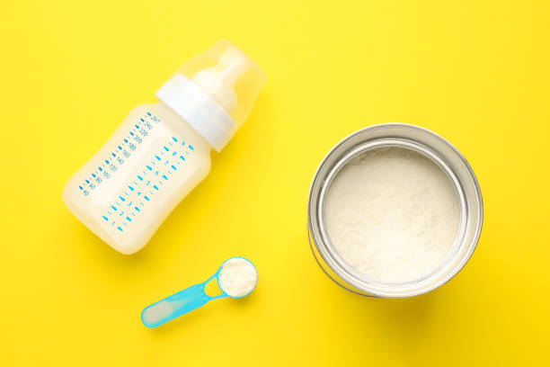 istock Feeding bottle with infant formula and powder on yellow background, flat lay 1403248511