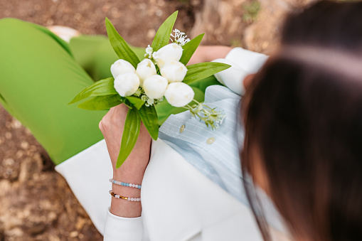 High-angle view of a young woman in a green and white suit holding snowdrop flowers while sitting on a bench in the park.