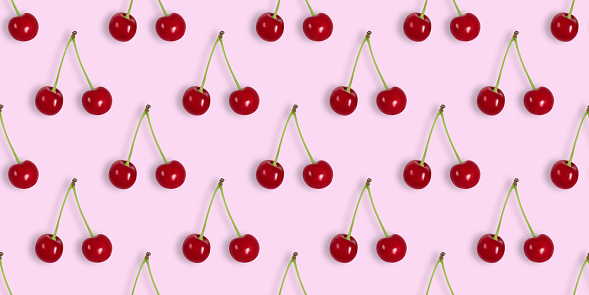 Seamless pattern with cherries on a pink background. Cherry seamless textures for design. Berry summer background. Top view, flat lay. Banner.