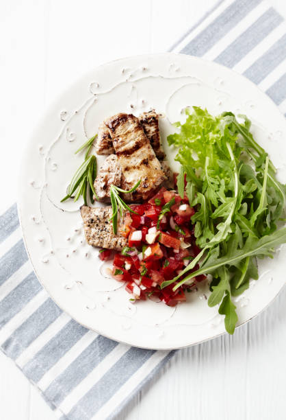istock Grilled Pork Tenderloin with Tomato Salsa and Arugula. Bright background. Top view. Copy space. 1403250332