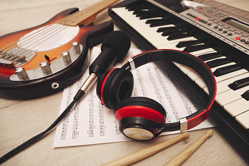 Different musical instruments, headphones and microphone on wooden background, closeup