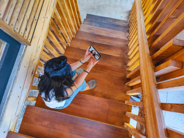 A staircase with a wooden railing and a vase on the bottom step. The vase is filled with flowers and is placed on a table. The staircase is made of wood and has a natural, warm appearance