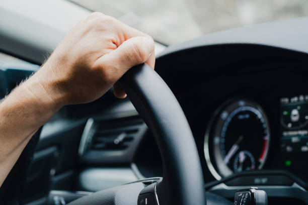 istock Male hands on a car's steering wheel 1403252279