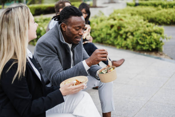 Multiethnic business people doing lunch break outdoor from office building - Focus on african man face stock photo