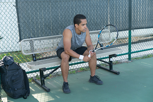Male player in a pause on a side of tennis court