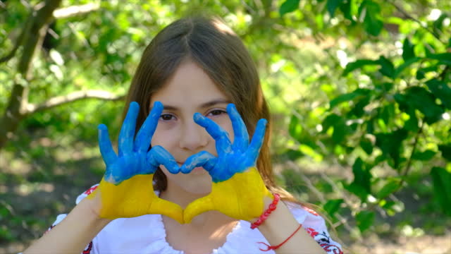 The Ukrainian flag is drawn on the child hands. Selective focus. Summer.