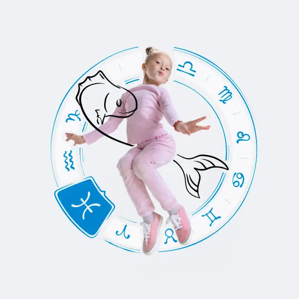 Photo of Creative portrait of happy little girl with drawing of zodiac signs isolated on light background with pencil sketches. Concept of birthday, person's character, year, horoscope