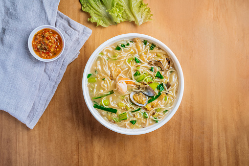 singaporean food Xinghua Lor Mee in a dish with chili sauce, and king's salad leaf top view on wooden background