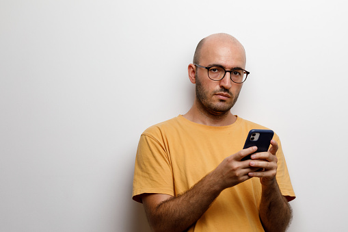 Young bald man with glasses, texting
