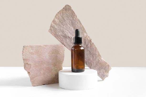 Dark amber glass bottle standing on stone. Natural skin care SPA beauty product design. Mineral organic oil cosmetics on beige background. Mock-Up. Oily pipette. Face and body treatment. Front view botella de vidrio ámbar oscuro de pie sobre piedra. diseño de producto de belleza spa para el cuidado natural de la piel. cosmética de aceite orgánico mineral sobre fondo beige. maqueta. pipeta aceitosa. tratamiento facial y corporal. vista frontal