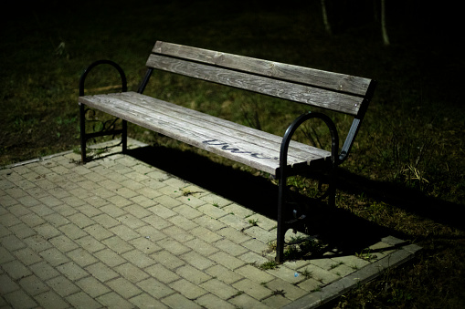 Bench in park at night. Place to relax in park. Empty shop on street.