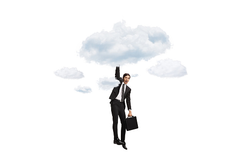 Businessman hanging from a cloud and holding a briefcase isolated on white background