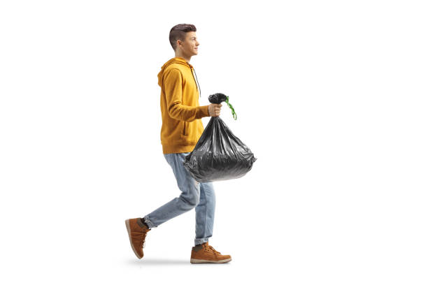 Full length profile shot of a casual guy carrying a plastic waste bag stock photo
