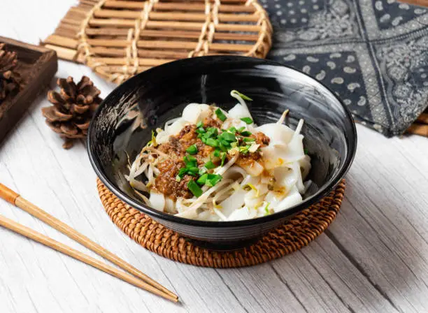 Photo of Big Kway Teow dry in a dish isolated on wood table side view taiwan food