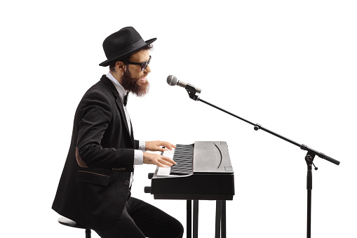 Musician playing keyboard and singing on a microphone isolated on white background