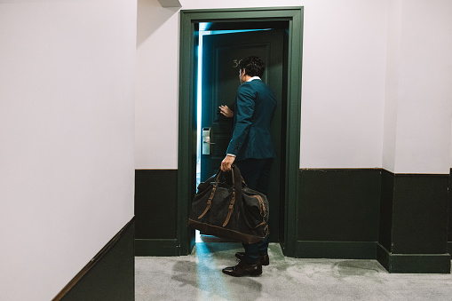 Businessman arrives at the hotel room. He is traveling for a business meeting.